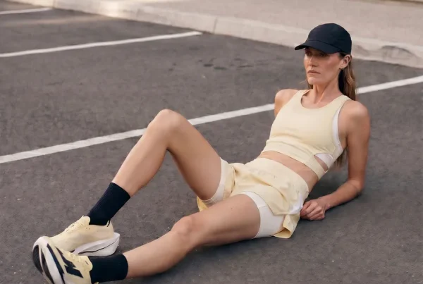 Runner in an "anti-performance" pose slouching against a raw brutalist concrete structure