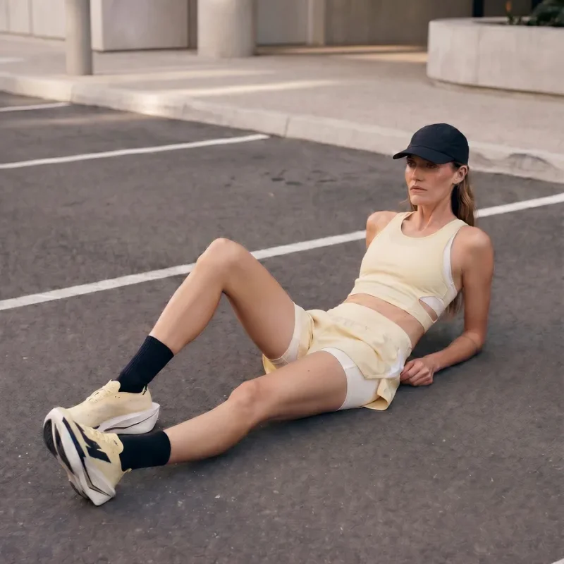 Runner in an "anti-performance" pose slouching against a raw brutalist concrete structure