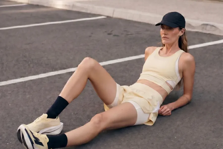 Runner in an "anti-performance" pose slouching against a raw brutalist concrete structure